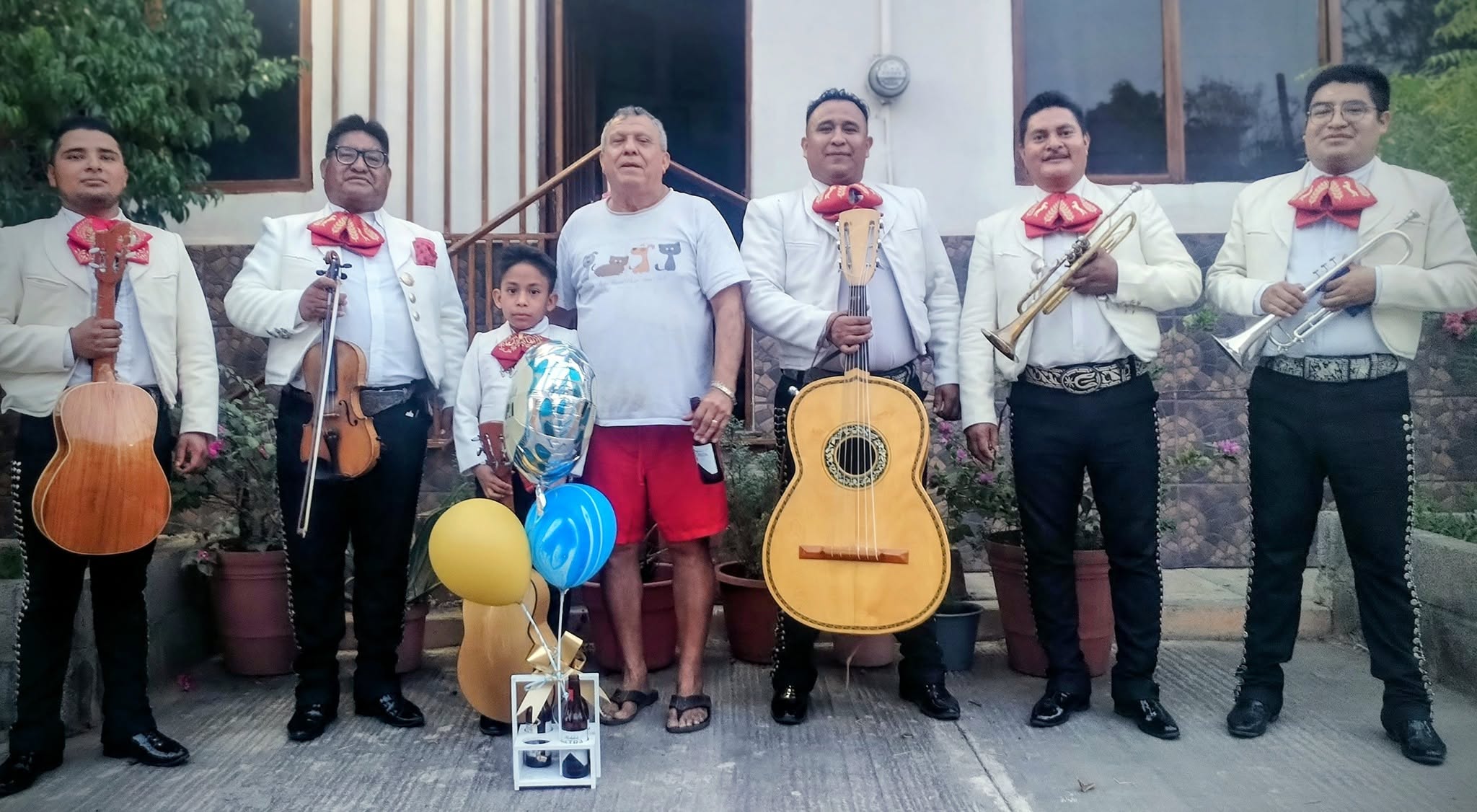 Músicos del Mariachi Juvenil Azteca posando junto al cliente anfitrión en su domicilio.